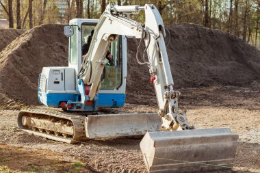 Kazıcı kazıyor. Craler Mini Kazıcı geniş kovayla toprak arka planında çalışıyor. Kazıcı katları. Kazı Çalışması. 