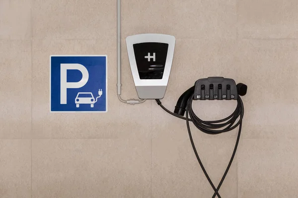 Electric Car Charging Slot with Power Cable Supply Plugged in Garage Car Parking. Charging Station. Eco-friendly alternative energy concept.