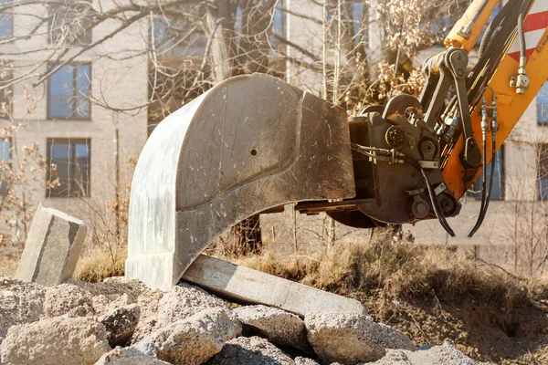 Construction Waste Recycling by Excavator Bucket Close up. Cleaning Stone Waste. Demolition of building. Freeing up space for construction of new building.