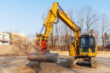 Excavator with Bucket working in Urban Place on Sunset.  Crawler Bulldozer digging in Public Park Residential Area