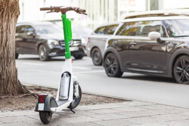 Electric Ride Paylaşımcı Scooter. Rıhtımsız scooter kiralık. Arka planda arabalar var. Şehir bisiklet taşımacılığı