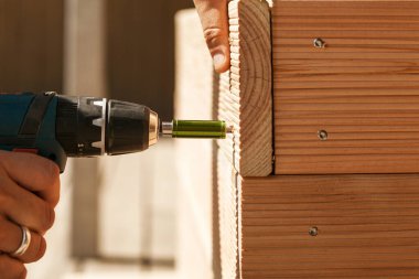 Matkapla tahta şeritlere vida takmak. Tahta kutuyla elektrikli tornavidayla düzüşen tahta işçisi. Ahşap çalışma konsepti