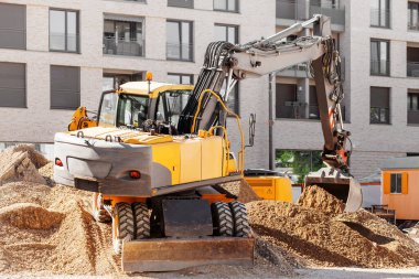 Kazıcı arka planda inşaat alanında kazı yapıyor. Kentsel caddede zemini olan Traktör Toprakları.