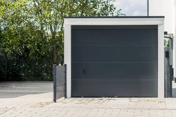 Private garage with automatic door in European city in Germany. Modern gray garage, Scandinavian-style house. Roll-up  Garage Gate.