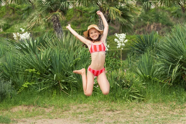 Çocuklar, Güneşli Yazda Tropikal Sahilde Tatil Yapıyor. Yeşil Doğa Arkaplanında Tropikal Kız Çocuk Neşeli Dans eden Zıplayan Eller. Boşluğu kopyala