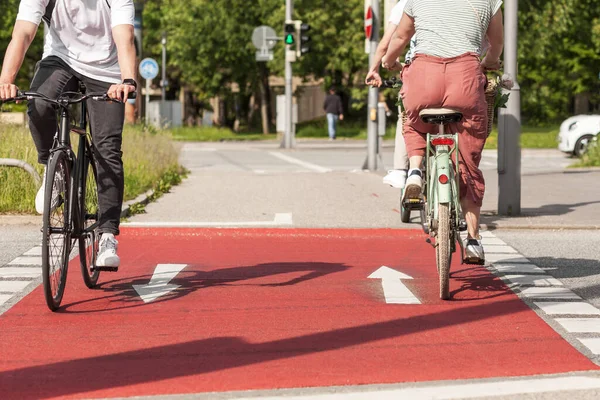 Cyclists on red bike path. Cycling on two-way bike lane. People ride bicycles in summer. Bike Traffic City Transport and people concept.