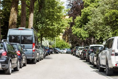 Arabalar yolun her iki tarafında sıra halinde park ediyorlar. Otoparkta arabalar. Trafik sıkışıklığında yoğun bir park yeri. Boş Otopark Sorunu.  