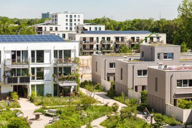 Munchen, Almanya - 05.19.2022: Modern konut binaları, güneş çatısı, büyük park ve oyun alanı olan apartmanlar. Green City, Eco House konsepti