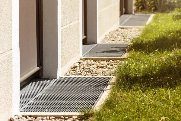 Drainage area around House. Drain for Water in front of Door. Pebbles for Water Drainage along House Wall. Drain Floor
