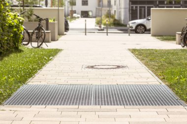 Drain Grating and Gutters for Drainage of Rainwater and Paving slabs on Cobblestone Sidewalk. Modern Footpath, Sidewalk in Urban Yards. 