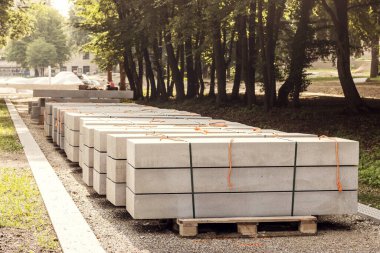 Concrete Slabs for Construction Pathway in Park. Concrete Blocks on Pallet. Pallet with stack of Concrete Curbstone. 