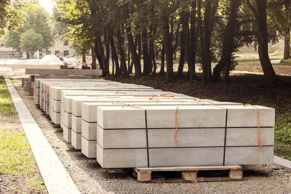 Concrete Slabs for Construction Pathway in Park. Concrete Blocks on Pallet. Pallet with stack of Concrete Curbstone. 