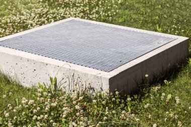 Ventilation shaft Outlet with metal grid on Ground Green Lawn. Modern Ventilation Grill Outlet or Air Conditioning of Underground Car Parking.