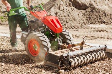 Toprak gevşetici traktör. Çimenlik için çakıl drenajı hazırlanıyor. Çimen grafiği için arazi hazırlanıyor.