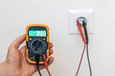 Testçi 'den Voltajı ölçüyorum. Elektrik Soketi Deliği 'nde dijital çoklu metre. Elektrik Servisi.