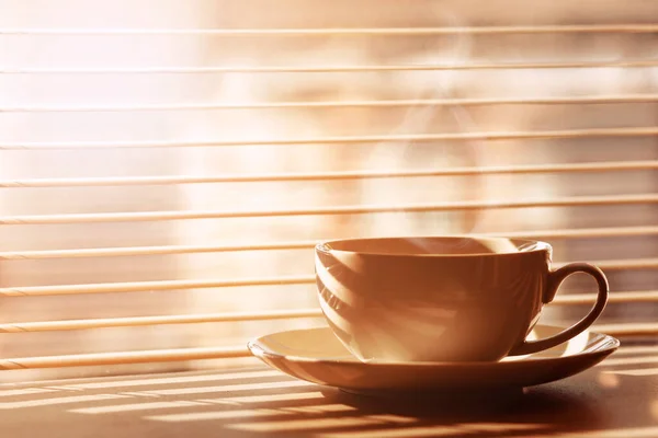 Coffee Cup with Steam on Cozy Window Sunrise Background. Good Morning with Coffee concept