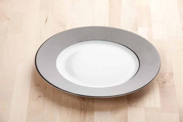 Empty white plate on wooden table — Stock Photo, Image