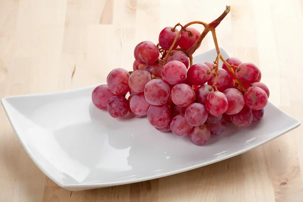 Тарелка с виноградом на столе — стоковое фото