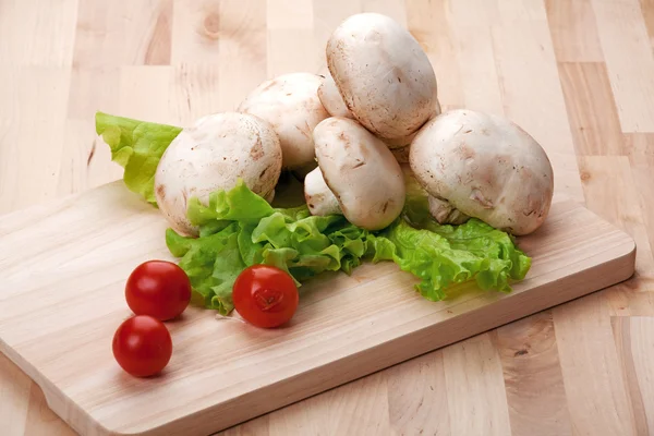 Cogumelos na mesa da cozinha com alface — Fotografia de Stock