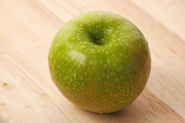 Зеленое яблоко на столе — стоковое фото