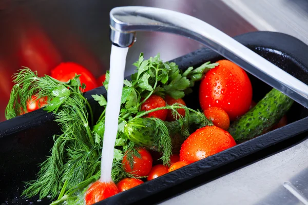 Le verdure vengono lavate nel lavello della cucina Foto Stock