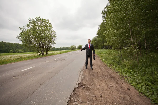 Empresario haciendo autostop en una carretera —  Fotos de Stock