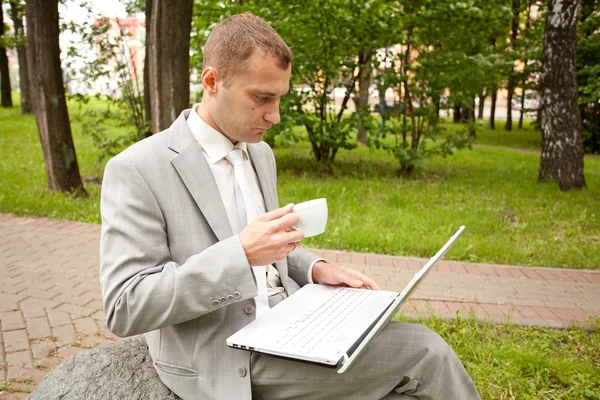 Zakenman die op laptop buiten werkt en een kopje koffie drinken — Stockfoto