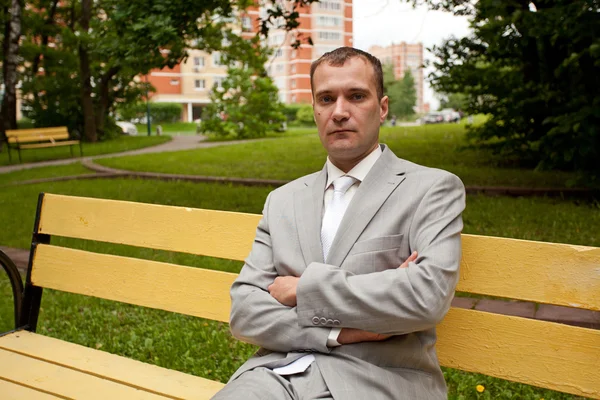 Young man in suit sitting on bench — Stock Photo, Image