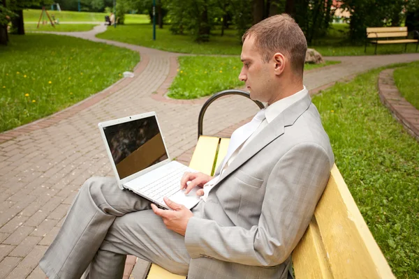 Empresario con cuaderno se sienta en el banco en el parque de la ciudad — Foto de Stock