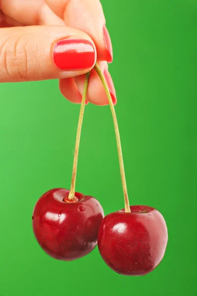 Female hand holding cherry, isolated on green background — Stock Photo, Image