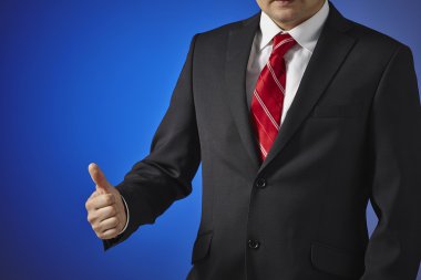 siyah elbiseli bir işadamı başarı el simgesi gösterir.