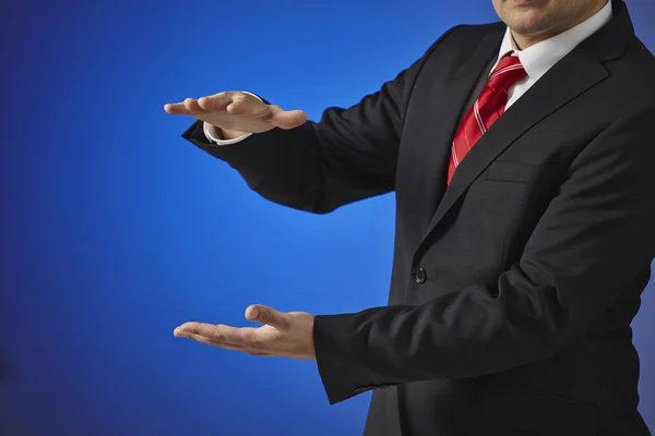 Businessman in a black suit shows the size of the hands — Stock Photo, Image