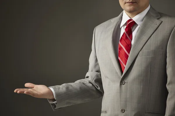 Businessman in a gray suit shows an empty hand — Stock Photo, Image