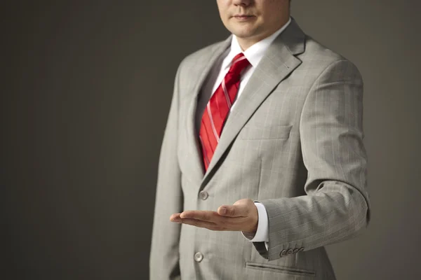 Businessman in a gray suit shows empty hand — Stock Photo, Image