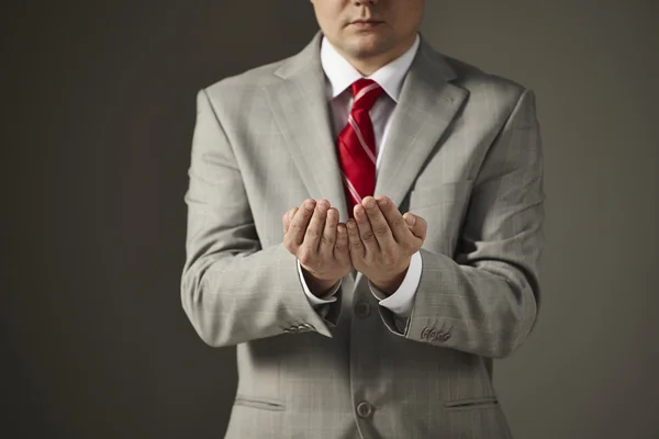 Zakenman in een grijs pak kijkt naar zijn handen — Stockfoto