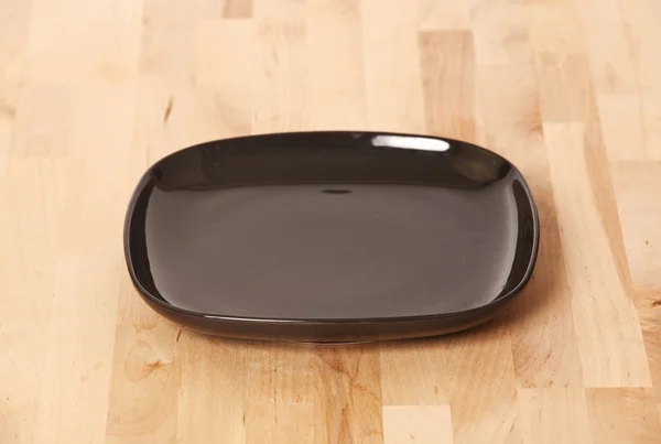 Black plate on kitchen table — Stock Photo, Image