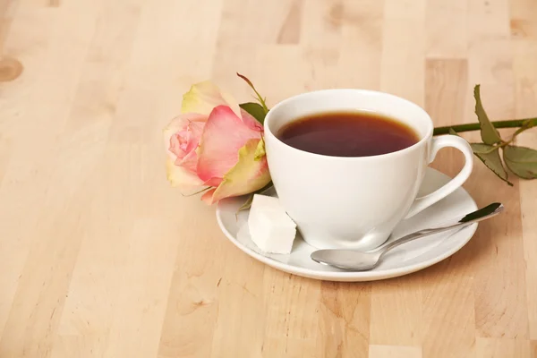 Teetasse und rosa Rose auf Küchentisch — Stockfoto