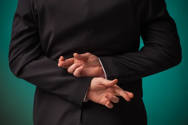 Бизнесмен держит за спиной скрещенный палец — стоковое фото