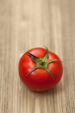 Fresh Single red tomato on wooden table . Close-up studio photog clipart