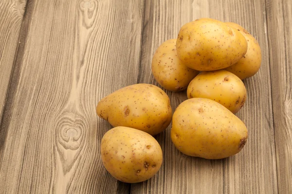 Raw potatoes on a wood table. Close-up studio photography. — Stock Photo, Image