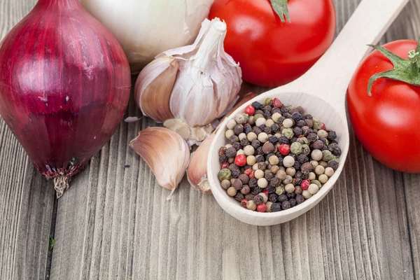 Fresh garlic, onion, tomato and pepper in a spoon on wooden tabl — Stock Photo, Image