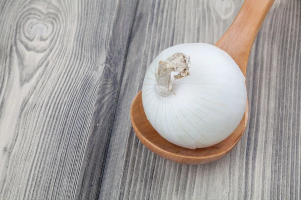 Cebolla cruda simplemente se ofrece en una cuchara de madera en la mesa de madera. Clos. — Foto de Stock