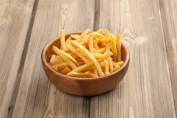 Frites dans un bol en bois, sur un fond en bois. — Photo