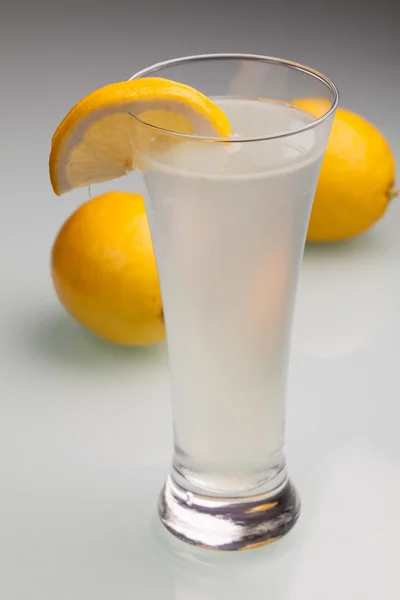 Glass of water and fresh lemon on a gray background — Stock Photo, Image