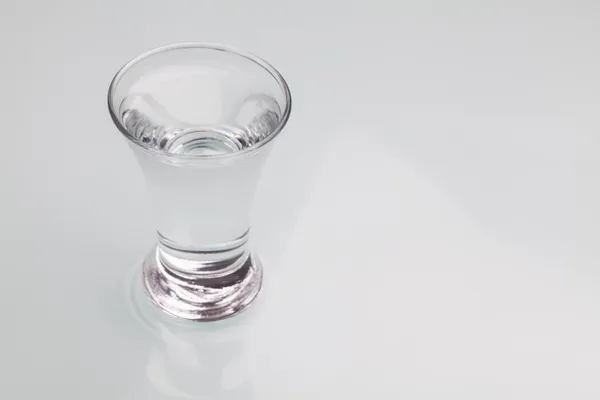 Small shot glass filled with alcohol isolated on gray background — Stock Photo, Image