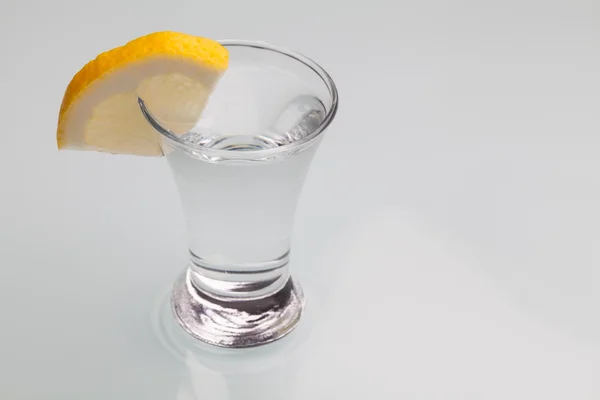 Glass of vodka with lemon isolated on gay background. Close-up s — Stock Photo, Image