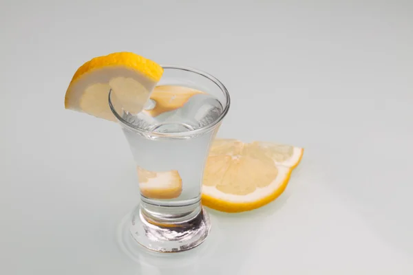 Glass of vodka with lemon isolated on gay background. Close-up s — Stock Photo, Image