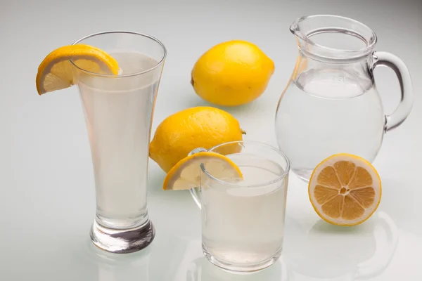 Jarra y vaso de limonada sobre fondo gris — Foto de Stock