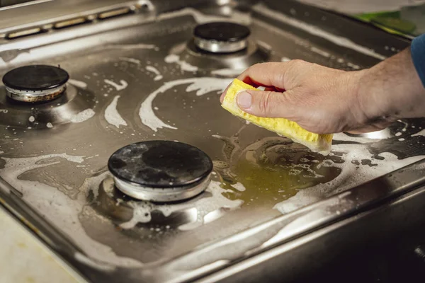 Hombre lavando estufa de gas con esponja amarilla, primer plano de la mano —  Fotos de Stock