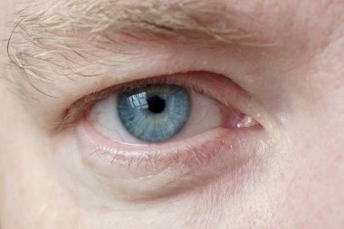 Beyaz bir erkeğin sağ gözü, yakın plan, yumuşak odaklı. Mavi gözlü insan gözü.